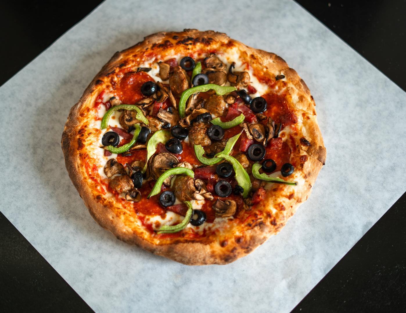 Supreme pizza with mushroom, olive, pepper, and pepperoni